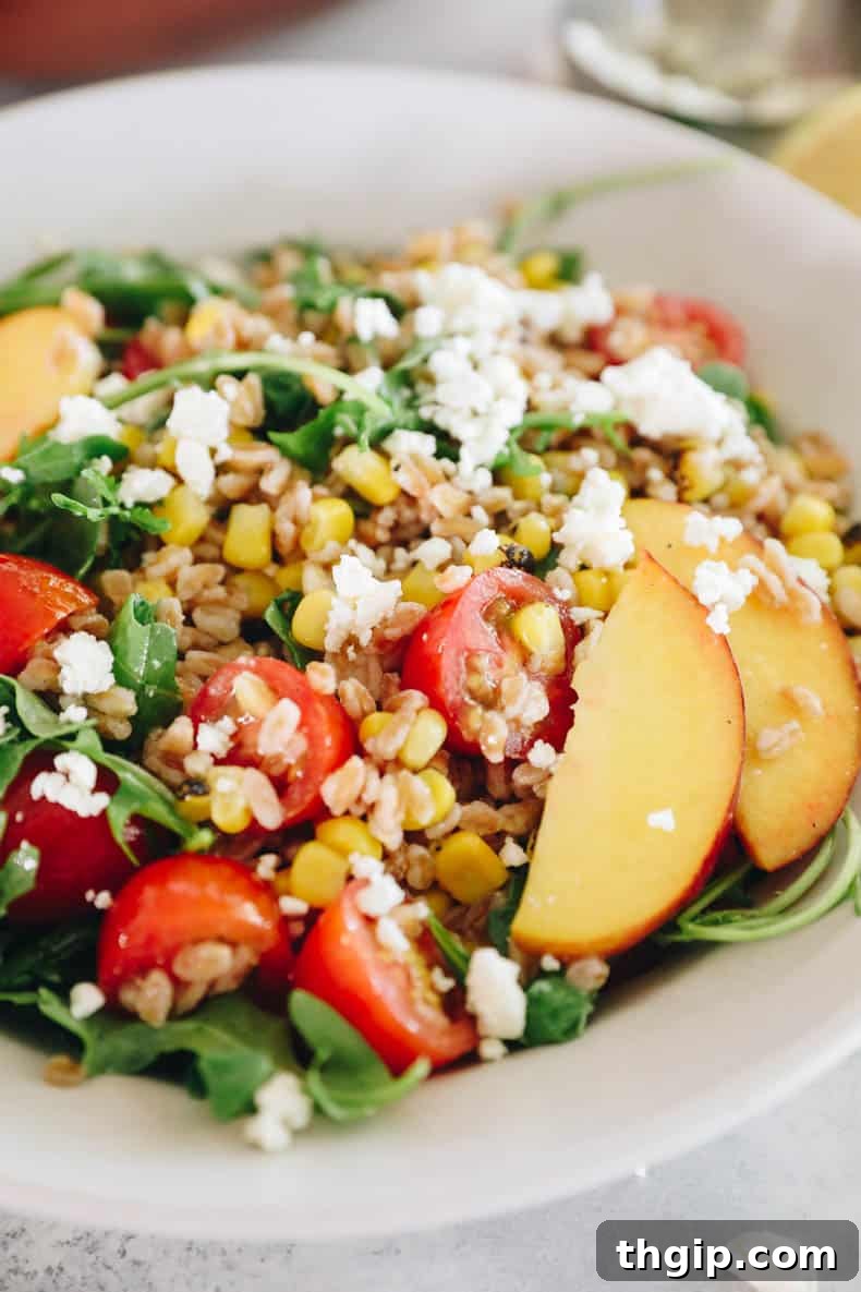 Vibrant Summer Farro Bowl 6 An inviting close-up of a summer farro salad, highlighting the texture of farro mixed with crumbled feta cheese, vibrant green arugula, sweet peach slices, and juicy cherry tomatoes.