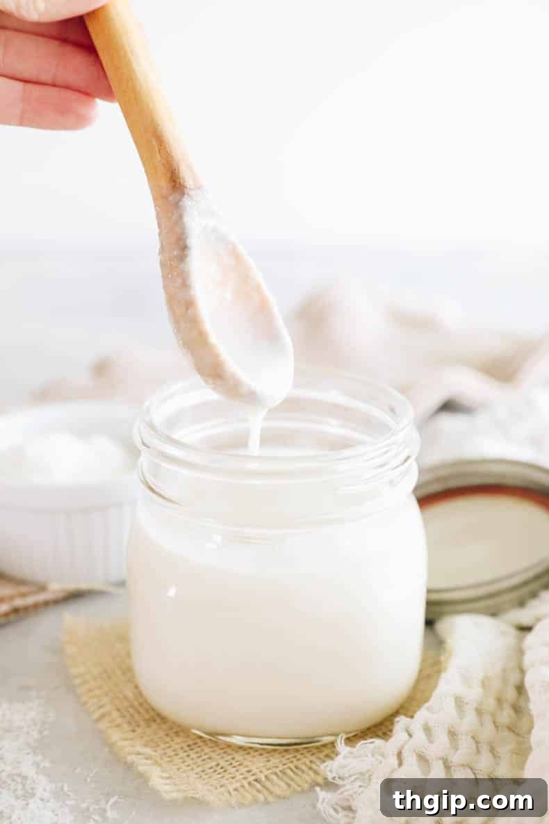 Drippy homemade coconut butter in a mason jar with a wooden spoon, ready to be enjoyed.