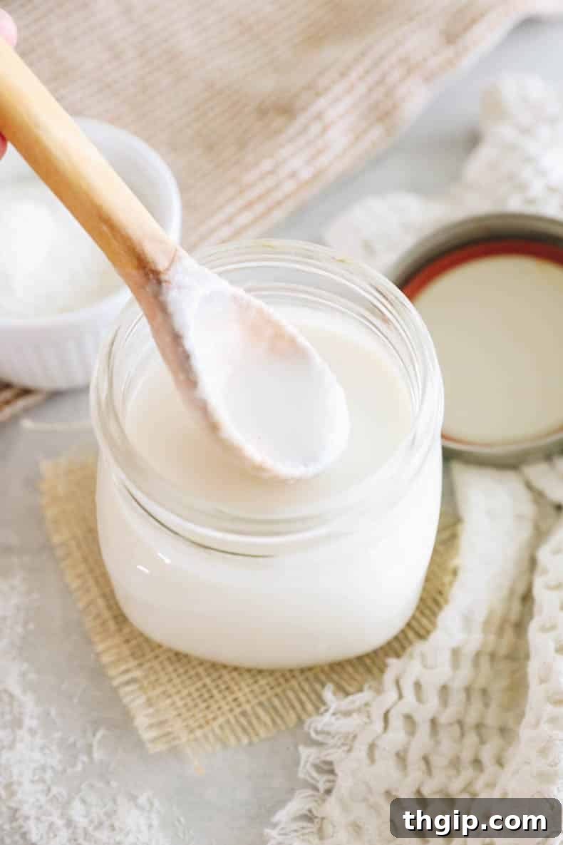Deliciously drippy homemade coconut butter on a wooden spoon, showcasing its creamy texture.