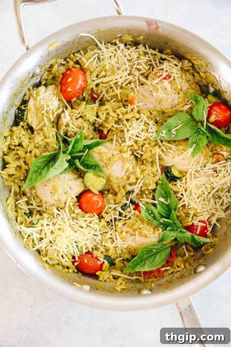 one pot pesto orzo with chicken, topped with parmesan cheese, ready to serve