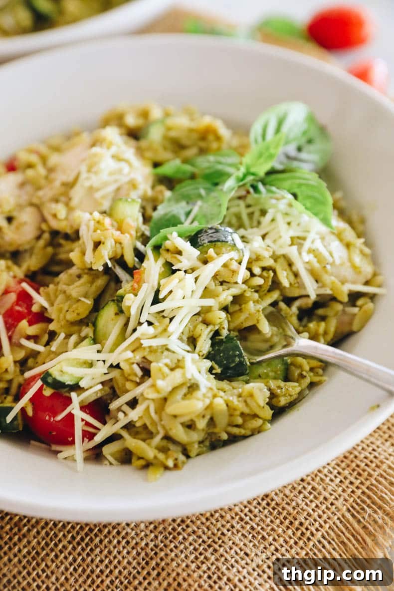 close-up of one pot pesto orzo and chicken, garnished with fresh basil leaves