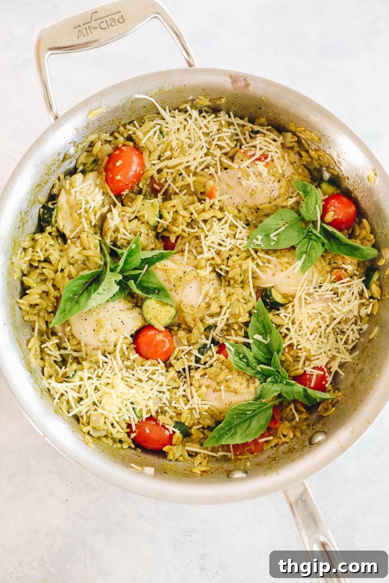 overhead shot of a large bowl of one pot pesto chicken and orzo, garnished with fresh basil leaves