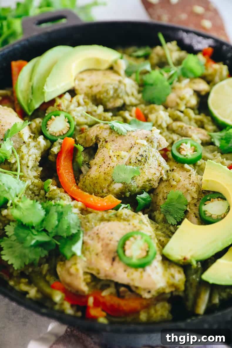 Zesty One-Pan Cilantro Lime Chicken and Rice 7 Close-up view of a succulent cooked chicken thigh nestled in rice and vegetables, served in a rustic cast iron dish.