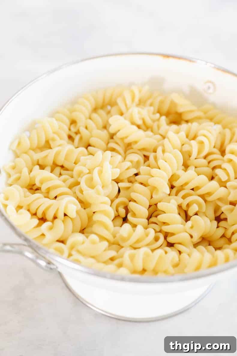 Mediterranean Pasta Delight 3 fusili noodles in a white colander being rinsed under cold water