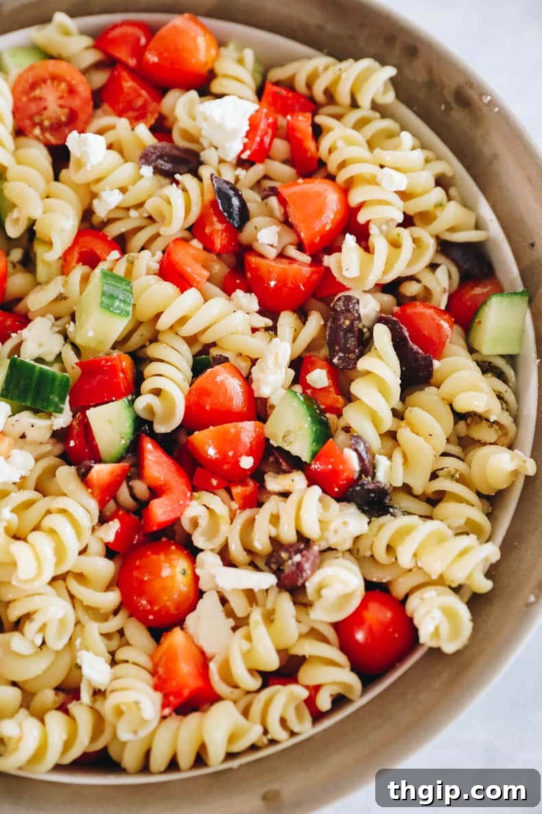Mediterranean Pasta Delight 5 Greek pasta salad in a white and brown bowl, fully mixed and dressed, ready to serve.