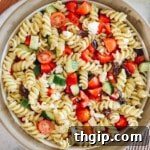 A large white and brown bowl with Greek pasta salad mixed together, ready to be served.