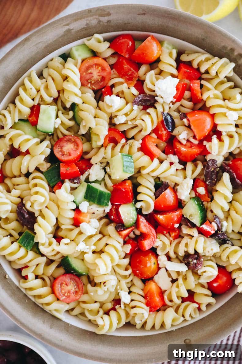 Mediterranean Pasta Delight 8 Overhead image of a large, rustic bowl filled with colorful Greek Pasta Salad, ready to be shared.