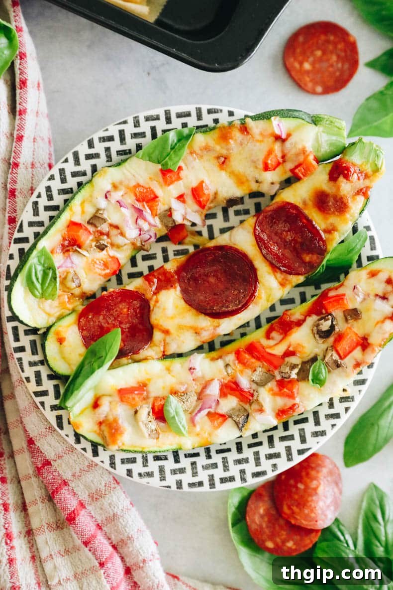 Pizza-Stuffed Zucchini 2 Three healthy zucchini pizza boats topped with various ingredients like cheese, pepperoni, and fresh basil, served on a stylish black and white striped plate.