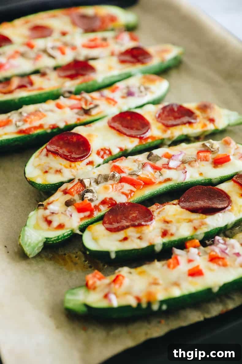 Close-up of baked zucchini pizza boats, hot from the oven with melted, bubbly cheese and fresh basil sprinkled on top.