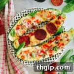 Zucchini pizza boats on a black and white striped plate, showcasing the melted cheese and fresh toppings.