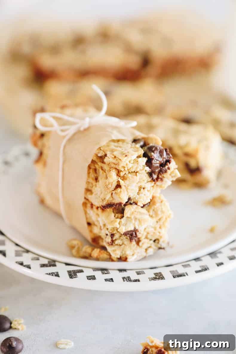 Power-Packed Protein Granola Bars 8 Stacked homemade high protein granola bars on a cutting board, garnished with oats and chocolate chips.