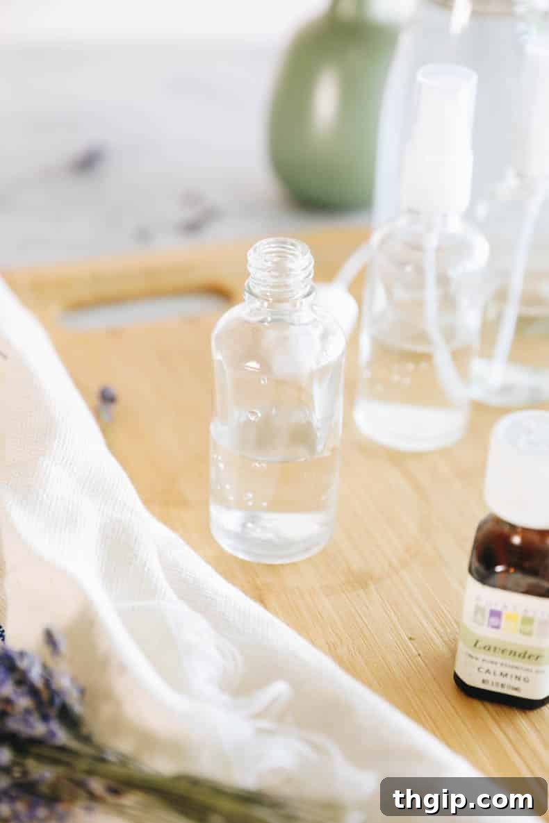 DIY Lavender Bliss Spray 4 Witch hazel being poured into a clear glass spray bottle, filling it halfway.