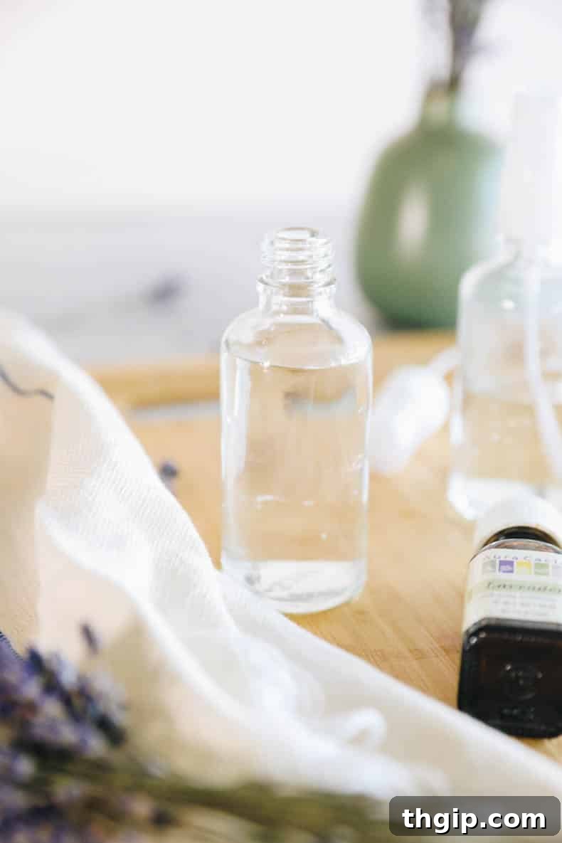 DIY Lavender Bliss Spray 5 Distilled water being added to witch hazel in a clear glass bottle, filling it almost to the brim.