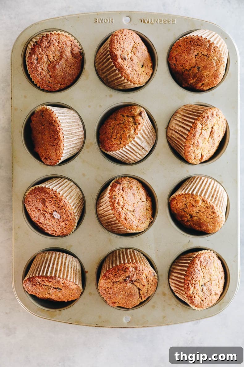 Almond banana muffins baking in a muffin tin, golden brown and puffed up.