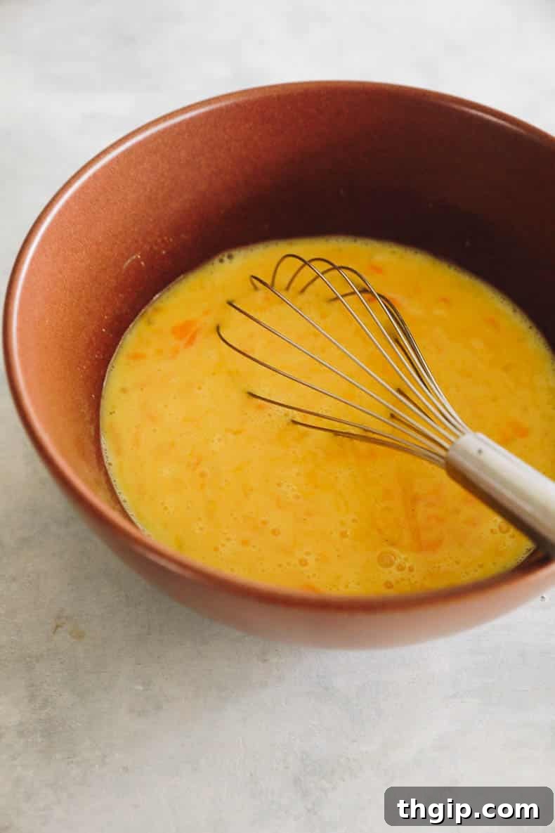 Whisked eggs and milk in a brown bowl, ready for the next step of the recipe.