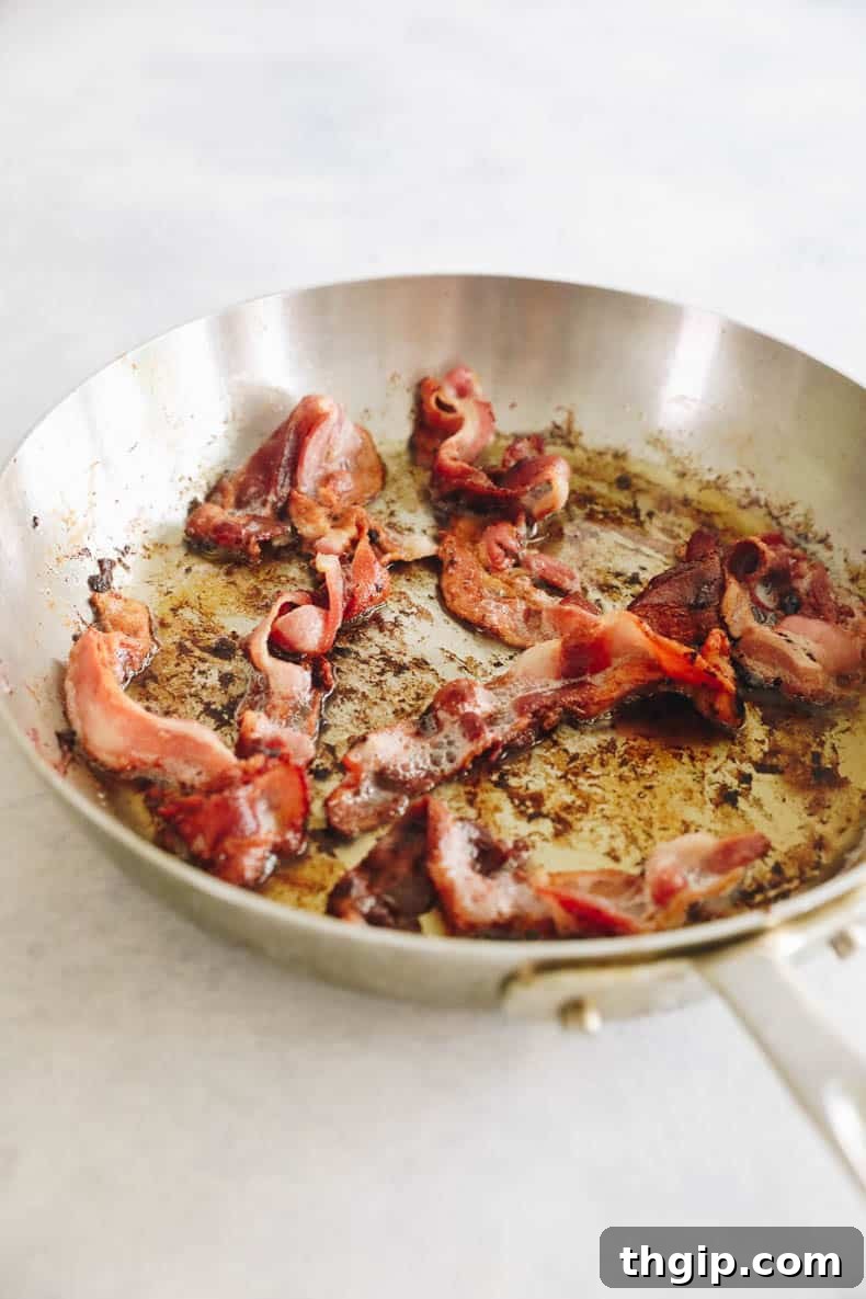 Crispy cooked bacon in a skillet, ready to be removed and chopped.