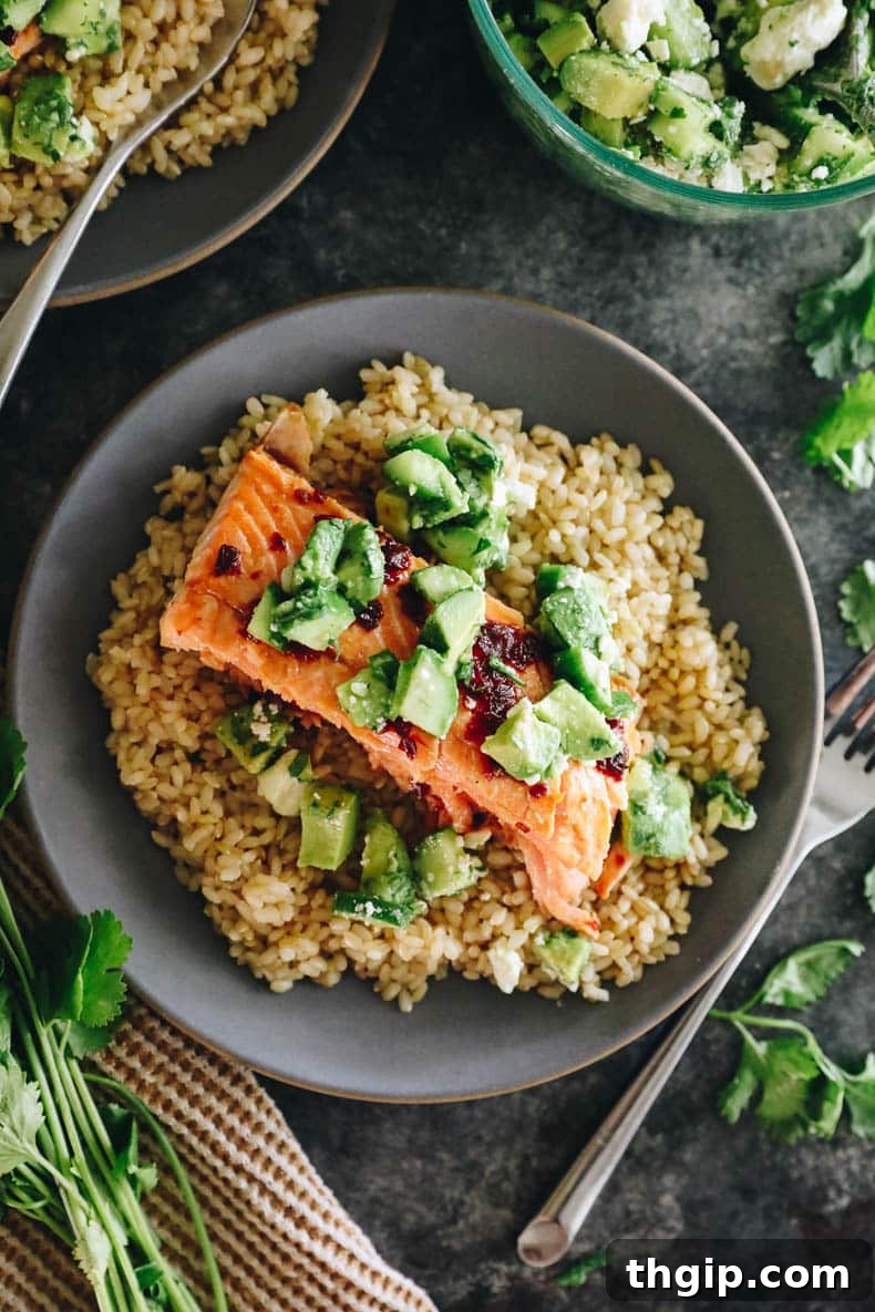 a blue plate with brown rice, baked salmon and avocado salsa.
