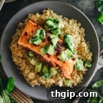 Chipotle baked salmon on a bed of brown rice with an avocado cucumber salsa plated on a blue plate.