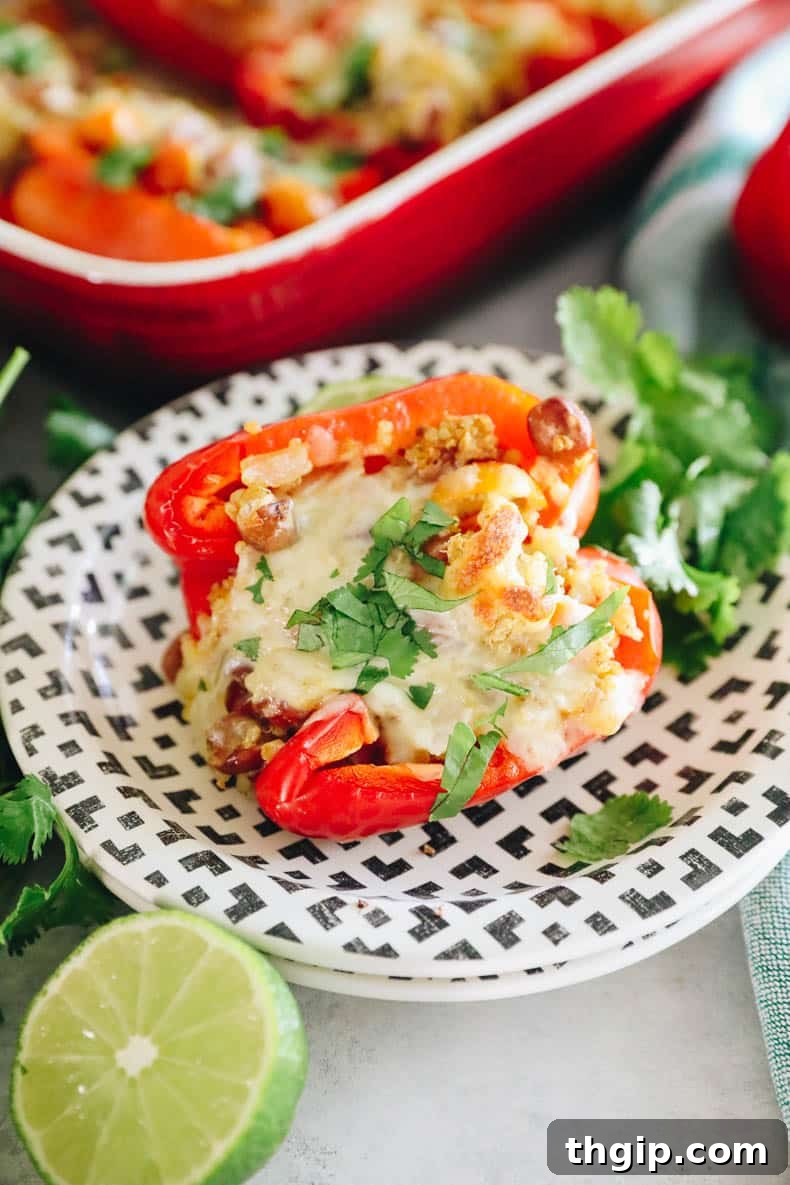 Vegetarian stuffed peppers with melted cheese and fresh chopped cilantro garnish, presented on a white plate.