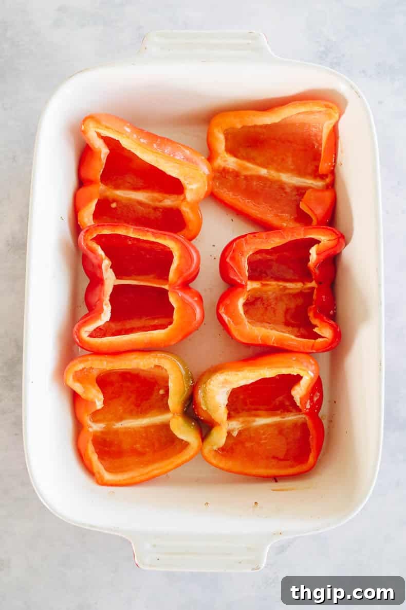 Baked red bell peppers cut in half and arranged on a baking sheet