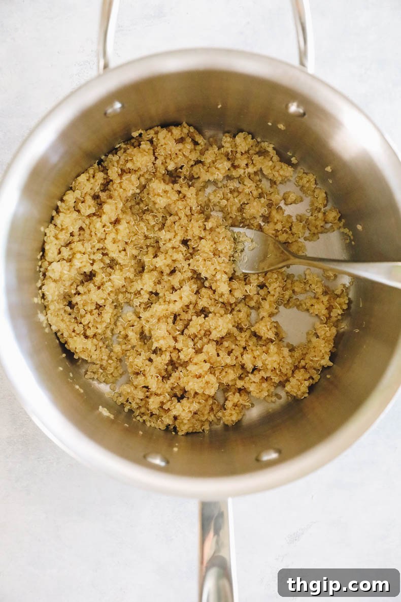 Close-up of cooked white quinoa in a pot, fluffed with a fork