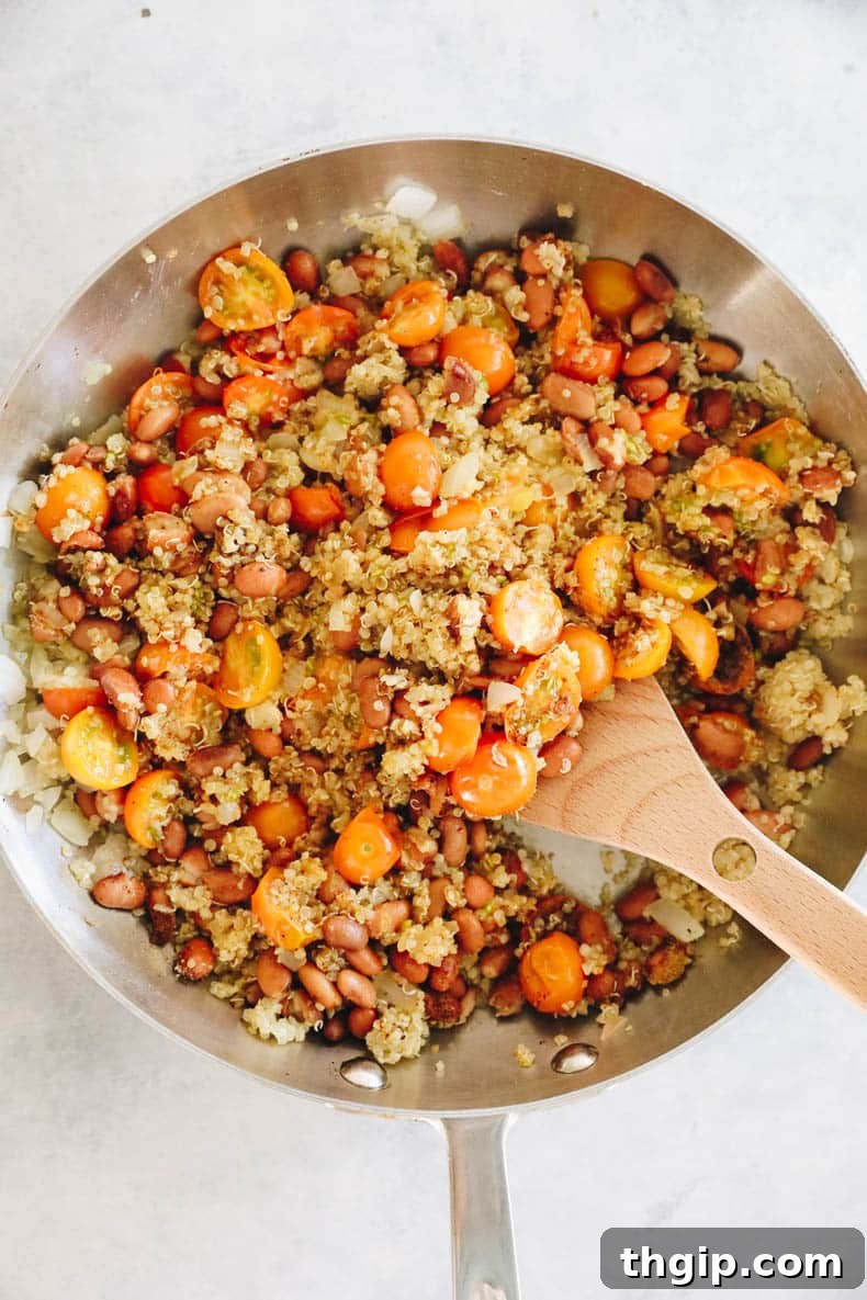 A vibrant quinoa stuffing mixture for bell peppers, with beans, tomatoes, and spices, in a skillet