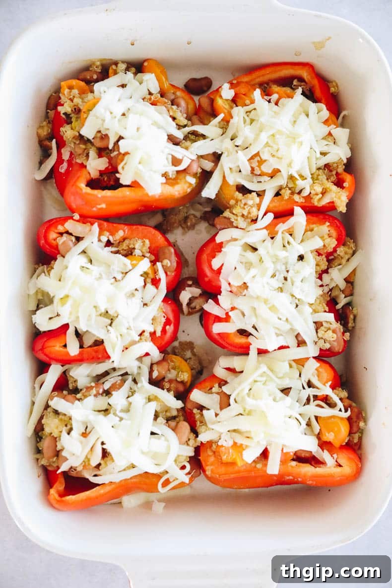 Quinoa stuffed peppers, freshly filled and topped with shredded mozzarella cheese, ready for baking