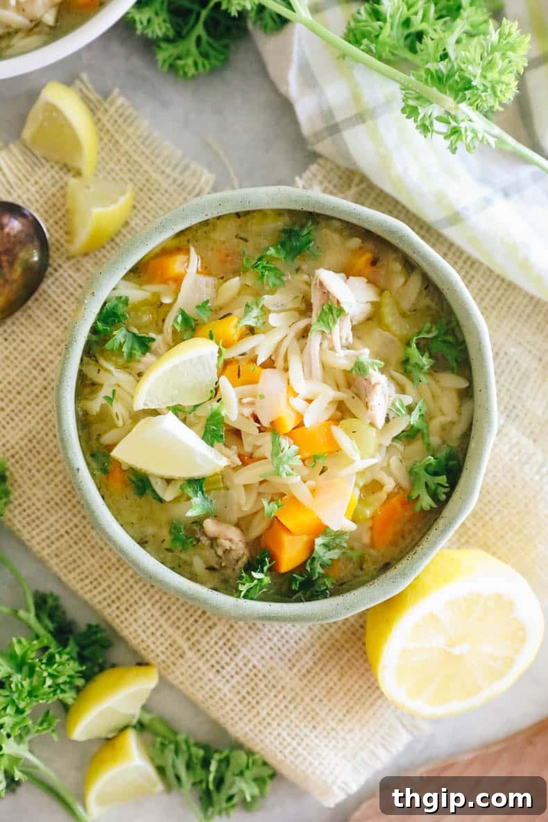 Lemon Chicken Orzo Soup in a vibrant green bowl, garnished with fresh parsley and lemon slices.