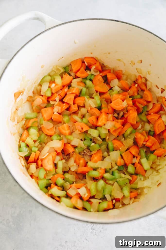 Diced onions, celery, and carrots sautéing in a pot, creating an aromatic base.