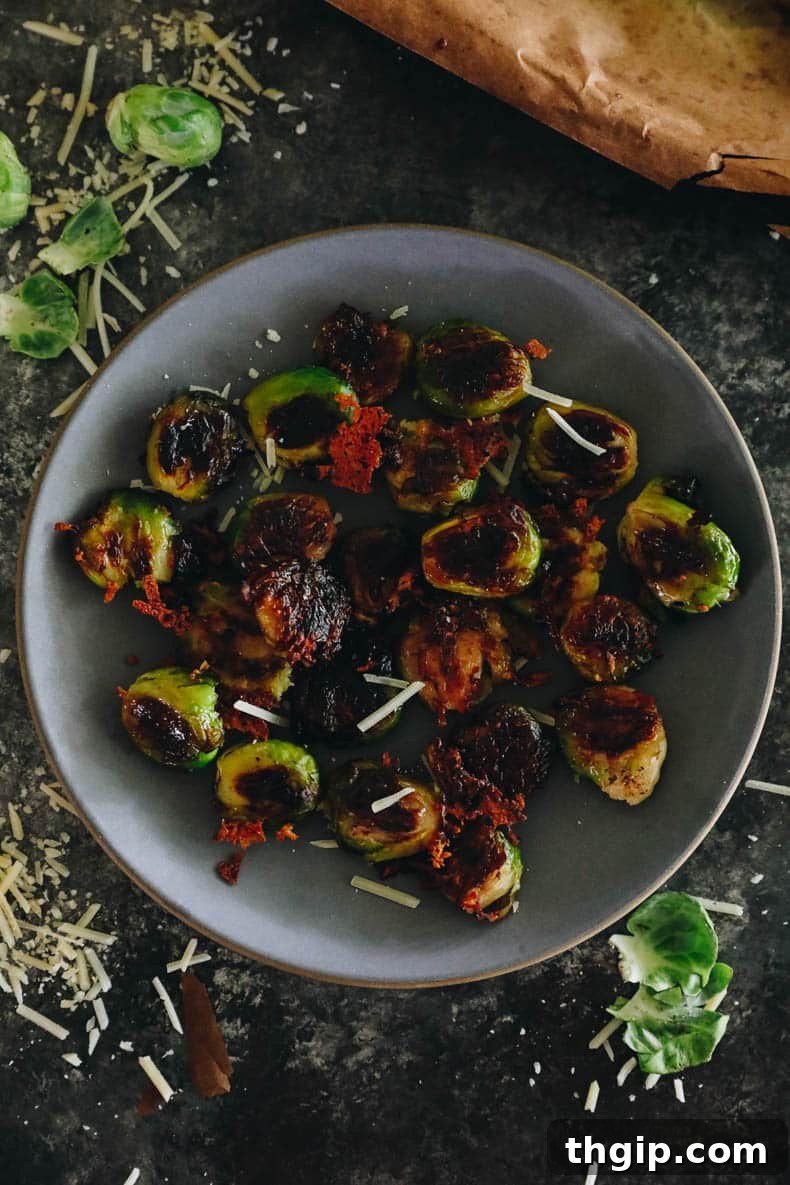 Golden Smashed Brussels Sprouts 2 Crispy smashed brussel sprouts with parmesan on a blue plate, garnished with fresh herbs.