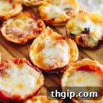 Close-up of baked mini tortilla pizza bites with melted cheese and pepperoni, resting on a rustic brown cutting board.