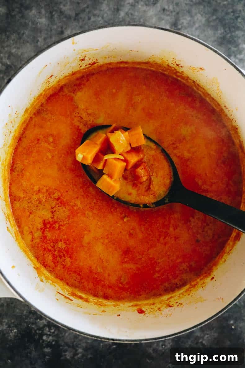 Rich, cooked sweet potato soup simmering gently in a white Dutch oven, ready for the next step.