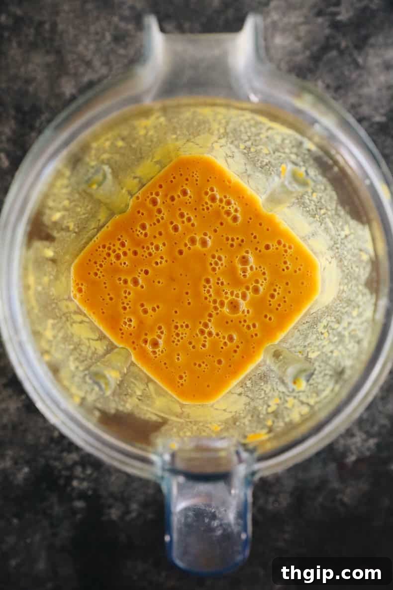 Creamy sweet potato soup being blended to a smooth consistency in a clear blender pitcher.