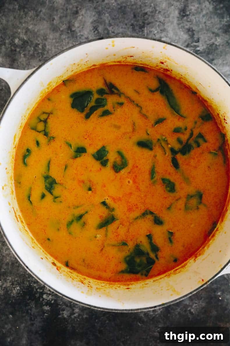 A vibrant bowl of curried sweet potato soup, rich in color and texture, with fresh toppings.