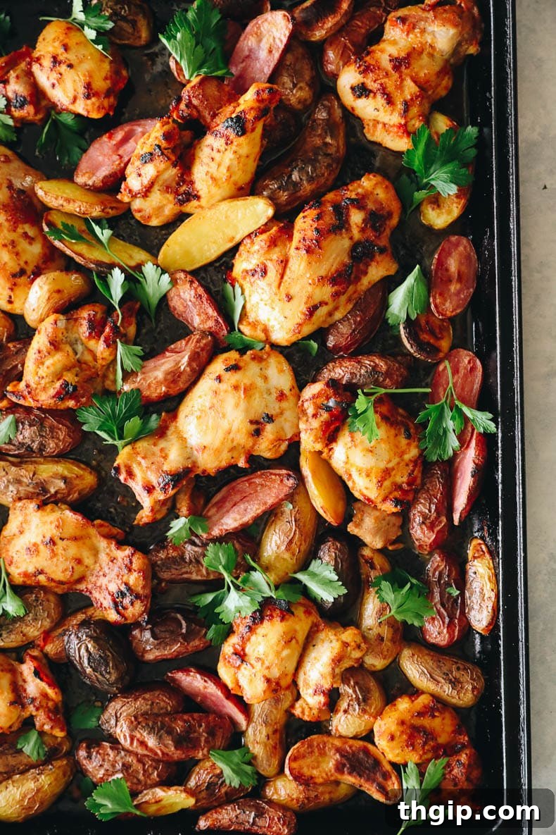 Chicken thighs and potatoes baking together on a sheet pan, nearly done.