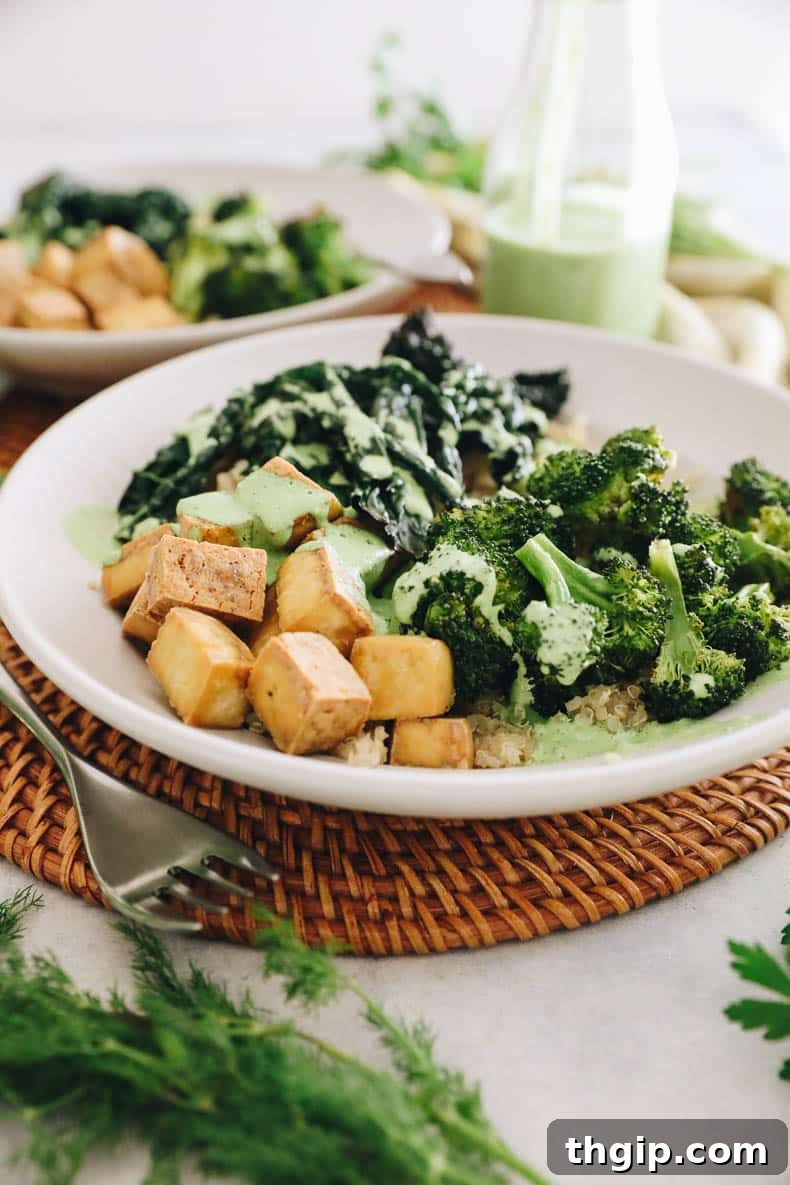 A vibrant Green Goddess Tofu Bowl with crispy tofu, quinoa, kale, and broccoli, drizzled with green dressing.