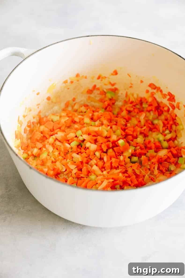 Mirepoix (chopped carrots, celery, and onion) sizzling in olive oil in a Dutch oven.