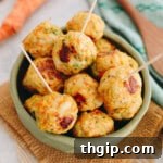 Baked chicken meatballs in a green bowl with toothpicks for easy serving.