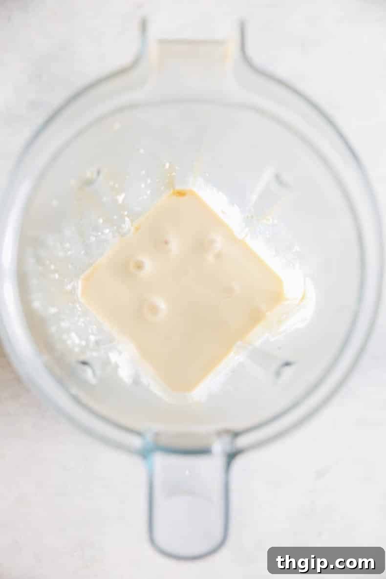 Cottage cheese, maple syrup, and vanilla extract blended into a smooth mixture in a blender.