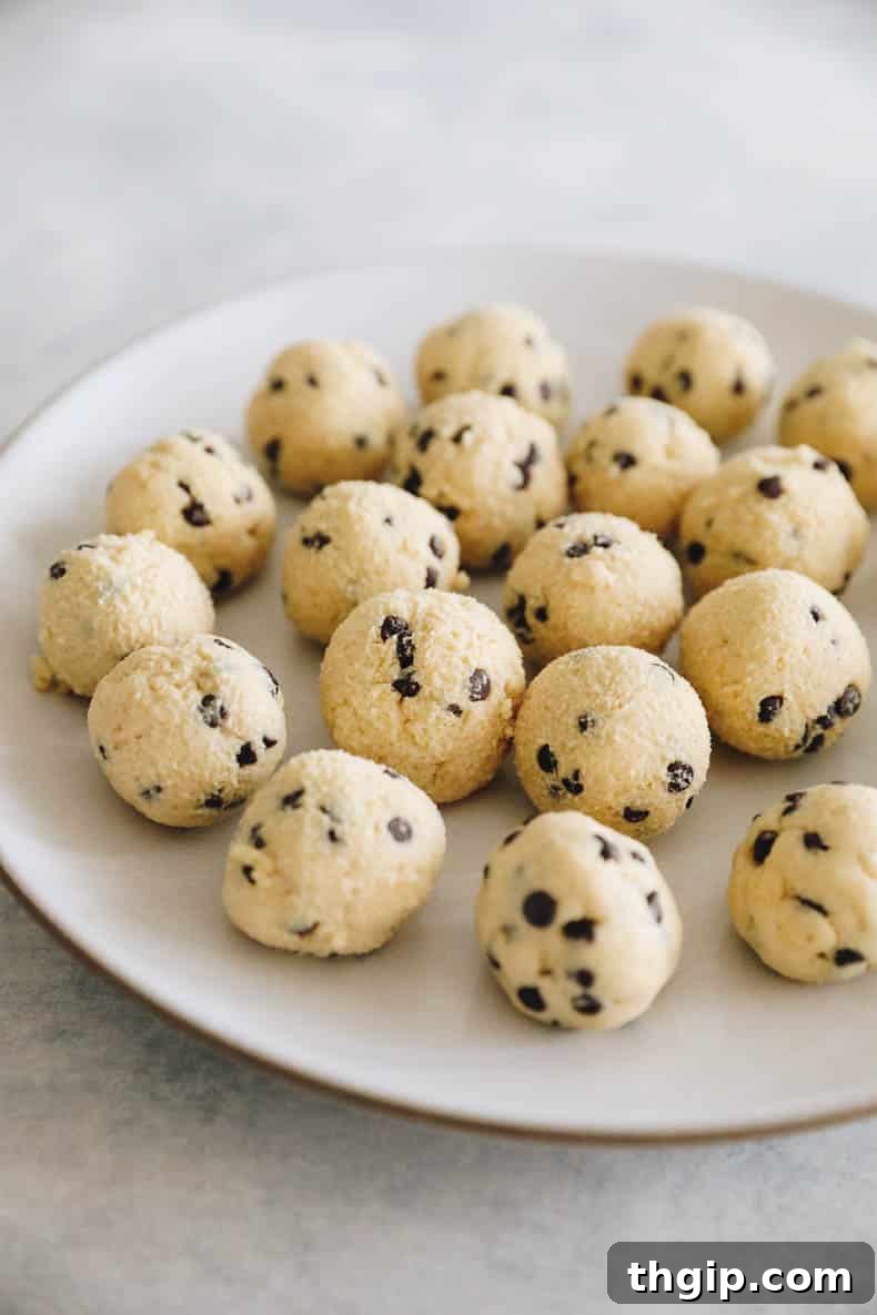 Cottage cheese cookie dough rolled into bite-sized balls with chocolate chips on a white plate.
