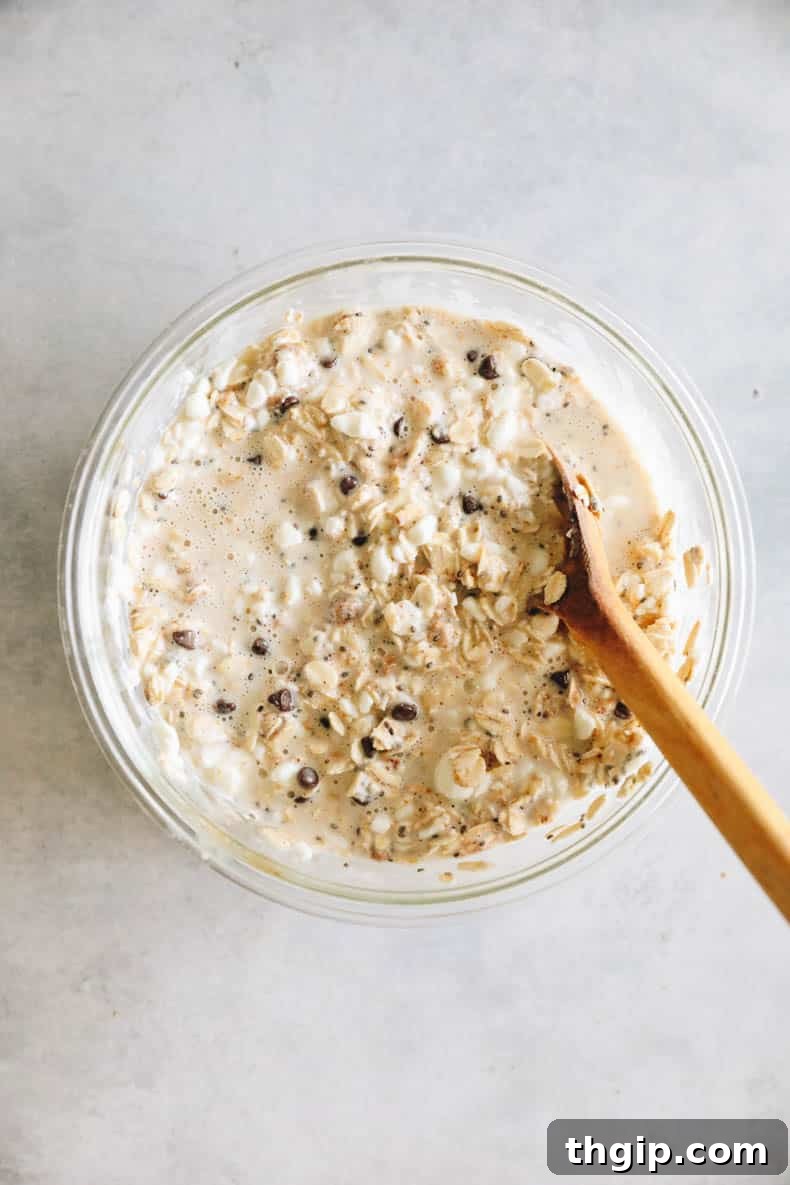 Creamy Cookie Dough Protein Overnight Oats 4 Cottage cheese overnight oats being mixed in a glass bowl before refrigeration.