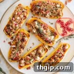 Stuffed delicata squashes with farro, pomegranate seeds, pumpkin seeds, pecans, and goat cheese on a white plate, ready for serving.