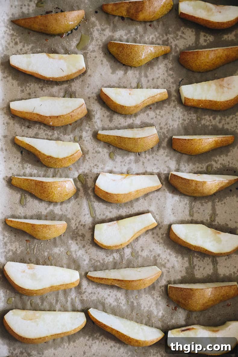 Caramelized Pear and Arugula Salad with Candied Walnuts 3 Carefully arranged roasted pear slices on a parchment-lined baking sheet, glistening with olive oil and a sprinkle of salt, ready for the oven.