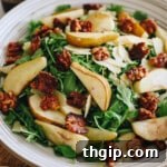 Caramelized Pear and Arugula Salad with Candied Walnuts 8 A delicious roasted pear salad presented in a large white salad bowl, complete with candied walnuts, shaved parmesan, and a drizzle of balsamic dressing.