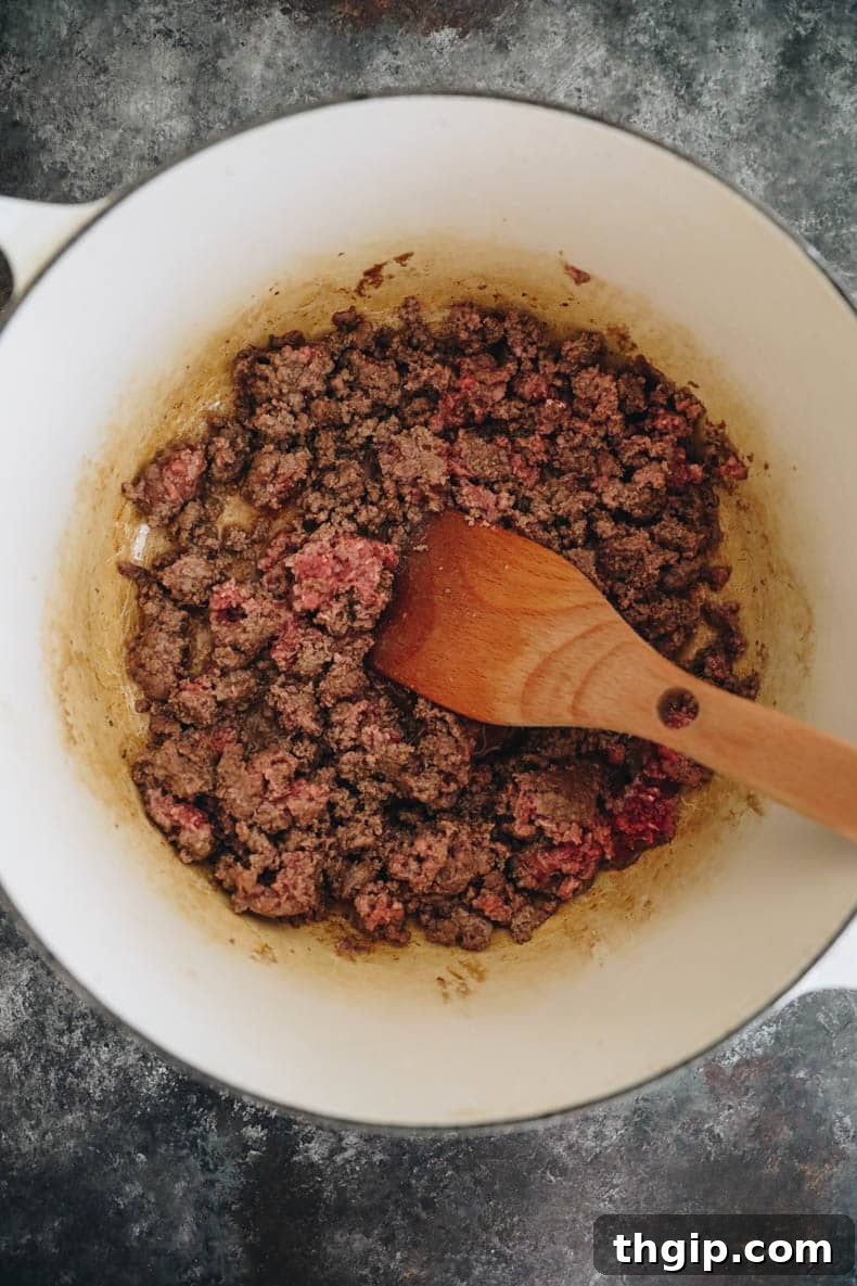 Texas-Style No-Bean Chili 3 Perfectly browned ground beef resting in a white Dutch oven, ready for the next steps.