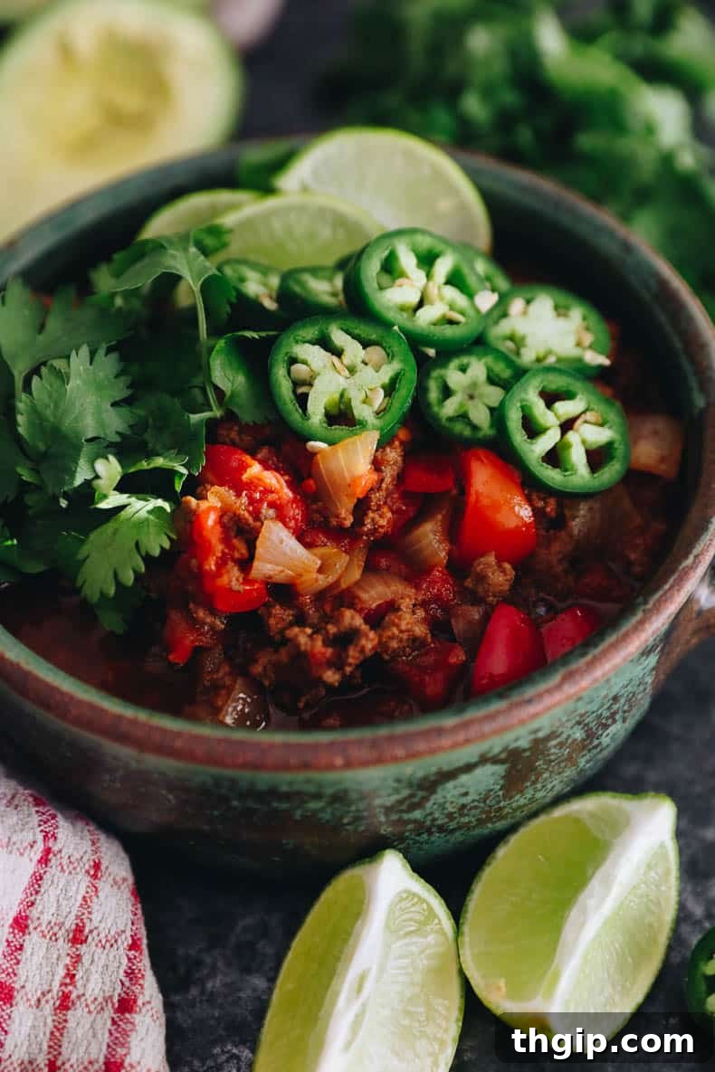 Texas-Style No-Bean Chili 6 A delicious bowl of no-bean chili, elegantly topped with fresh jalapeño slices, a bright lime wedge, and vibrant cilantro for a perfect finish.