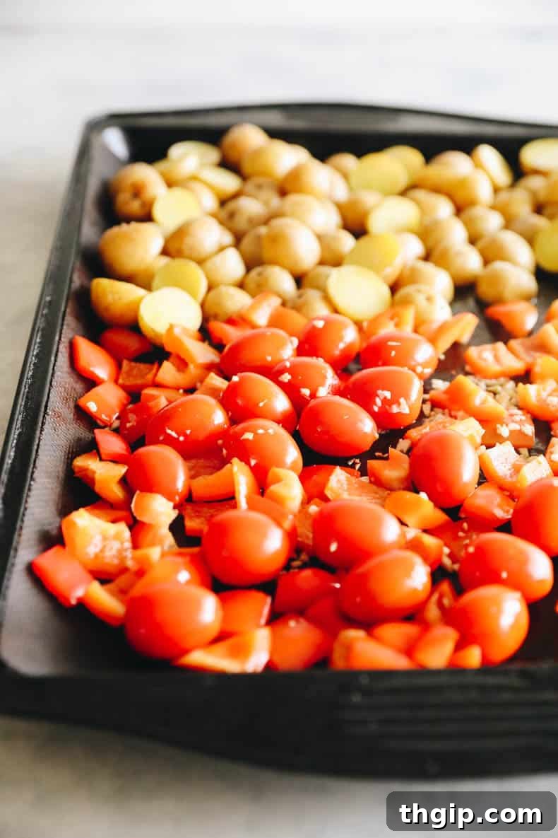 Lemon Herb Sheet Pan Cod 4 Vibrant cherry tomatoes, bell peppers, and potatoes roasting on a sheet pan, perfectly tender and slightly caramelized.