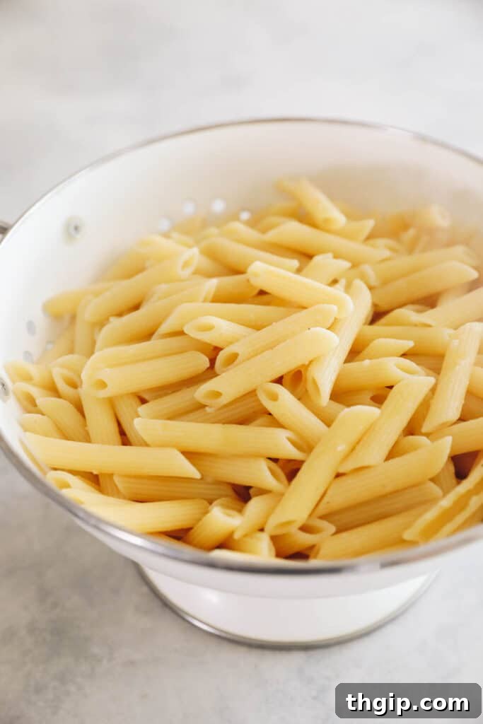 Hearty Chicken Sausage Pasta 3 Penne pasta being drained in a white colander after cooking to al dente.