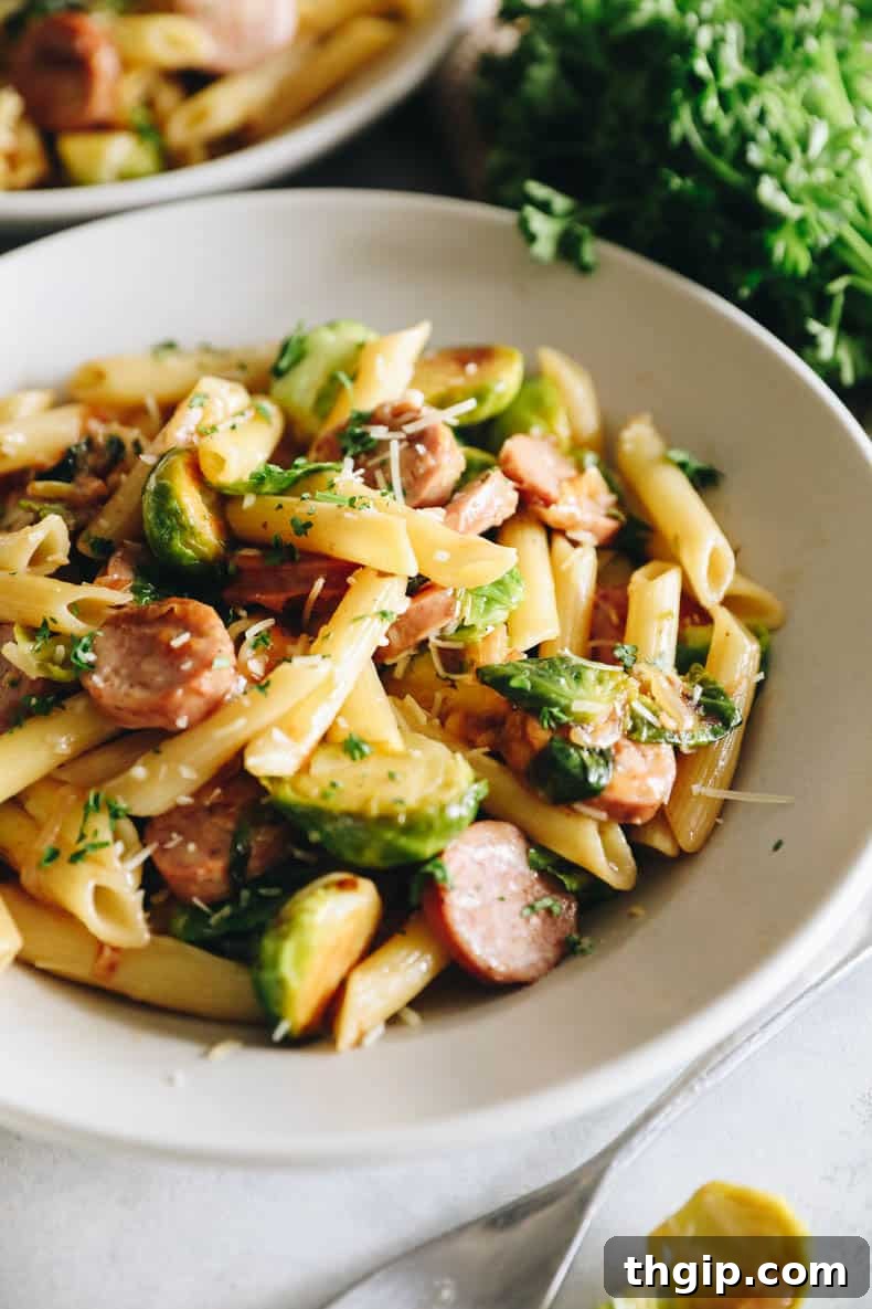 Hearty Chicken Sausage Pasta 6 Close-up of Chicken Sausage Pasta served in a white shallow bowl, garnished with parsley and Parmesan.