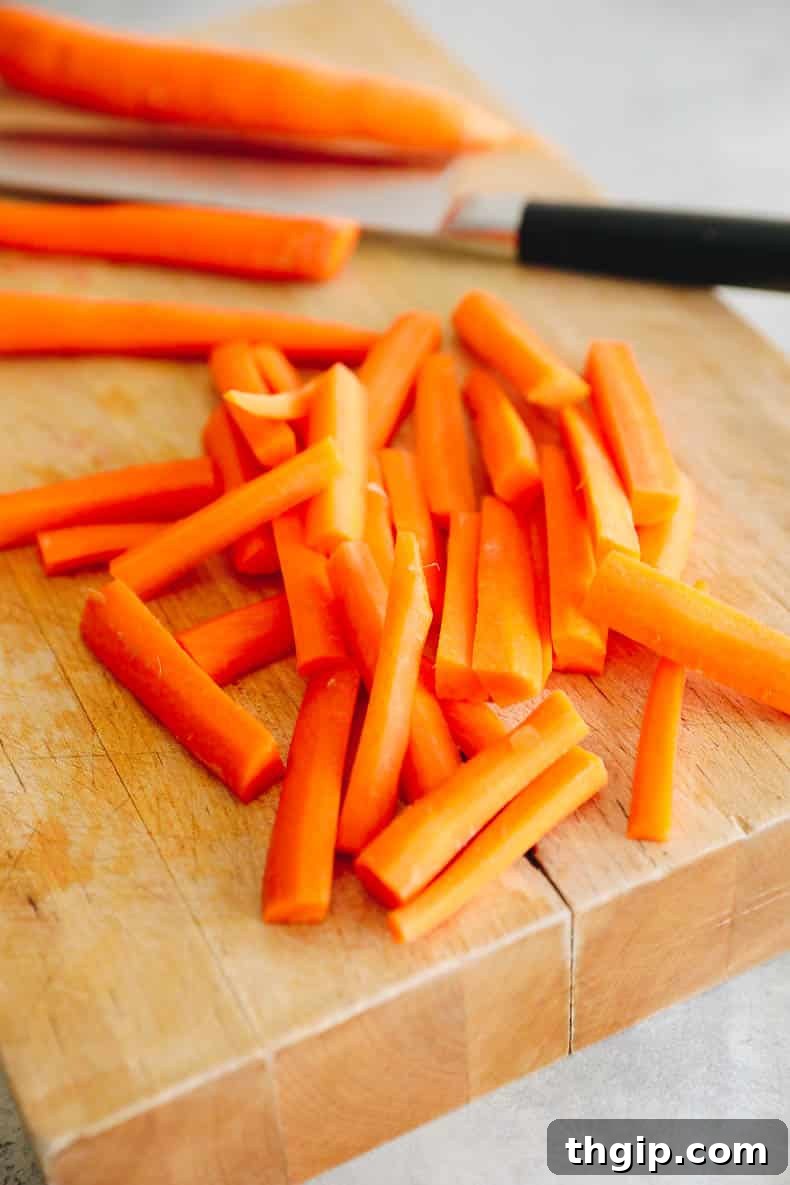Golden Oven-Baked Carrot Sticks 3 Carrots sliced into uniform fries on a cutting board, ready for seasoning.